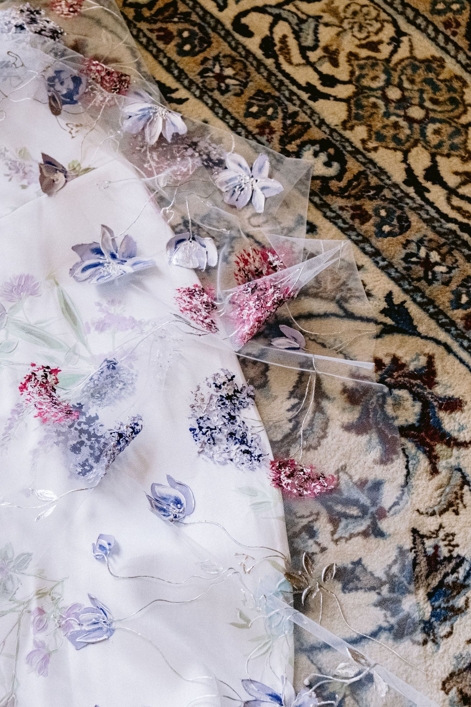 Delicate floral pattern fabric with blue and pink butterflies laid out on an ornate carpet.