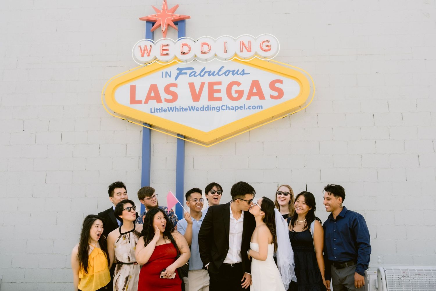 Classic Las Vegas welcome sign with wedding party gathered beneath it.