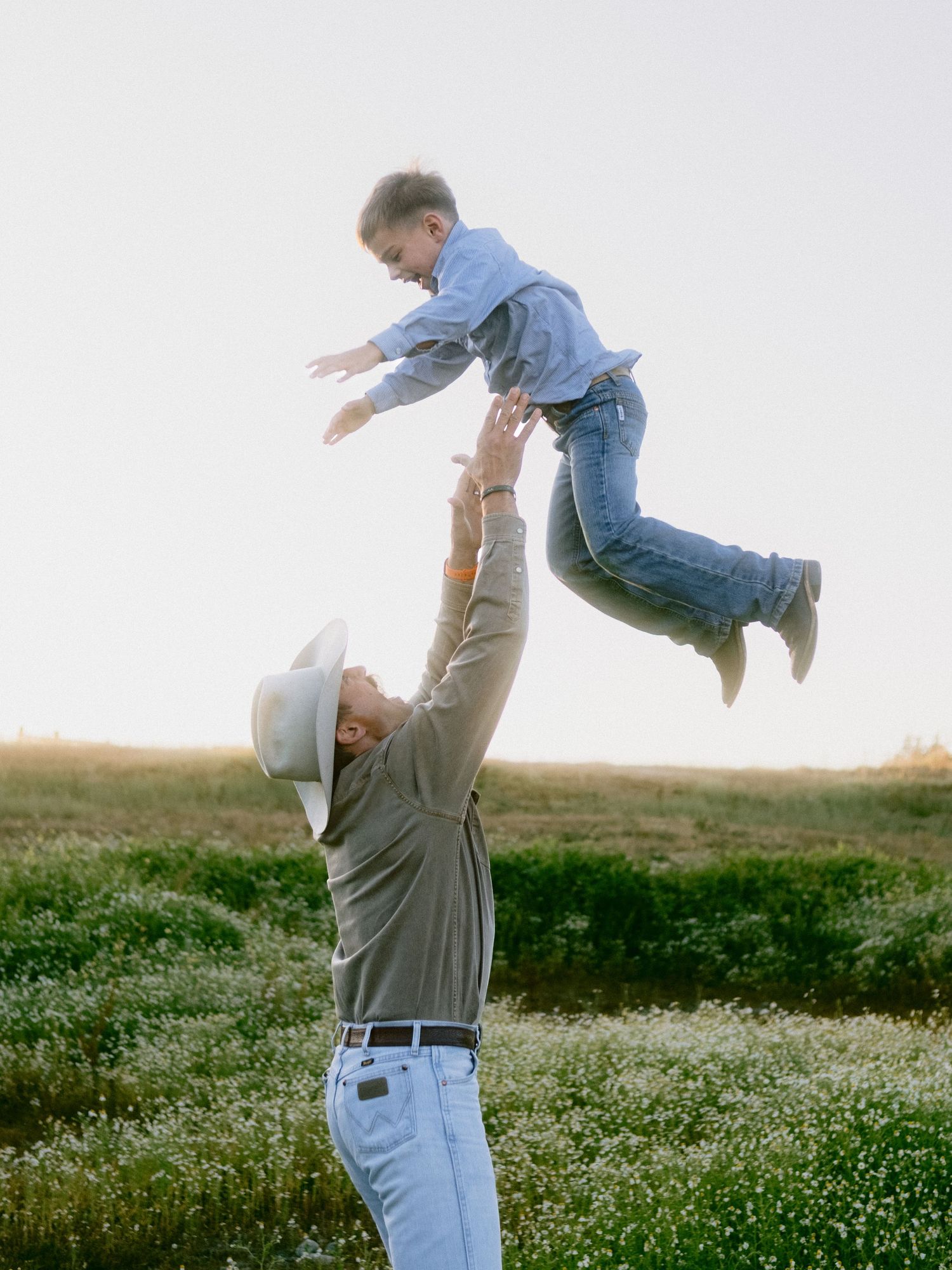 A playful moment between parent and child in a field of wildflowers at sunset.