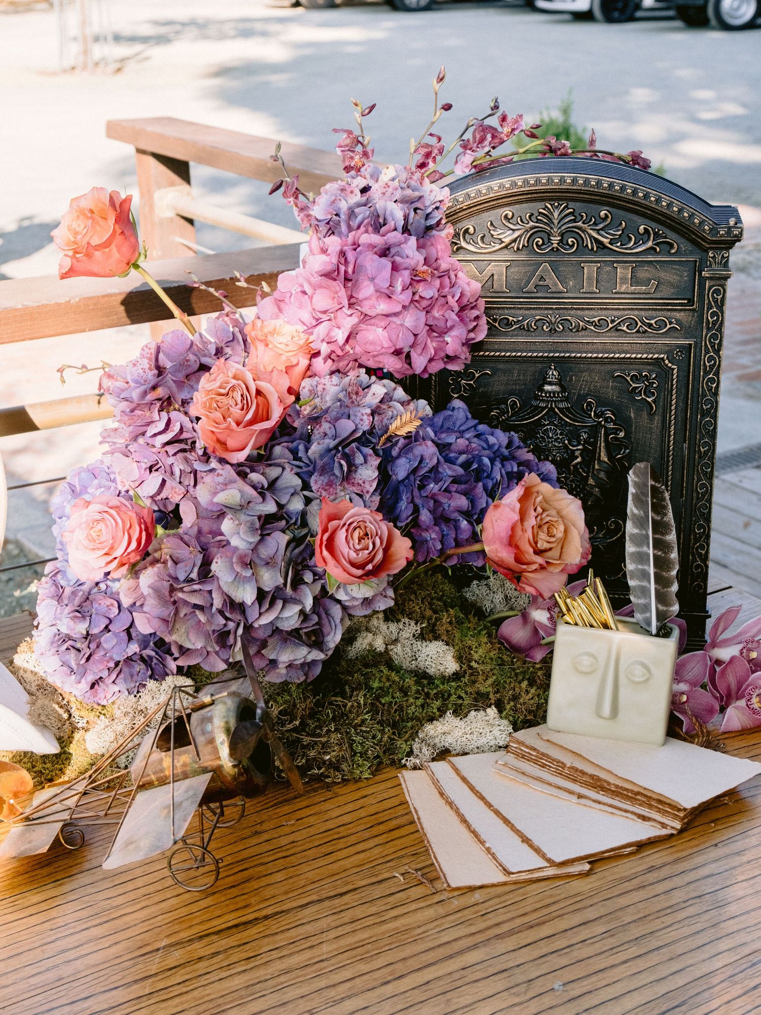 Elegant floral arrangements with pink and purple blooms on rustic wooden display.