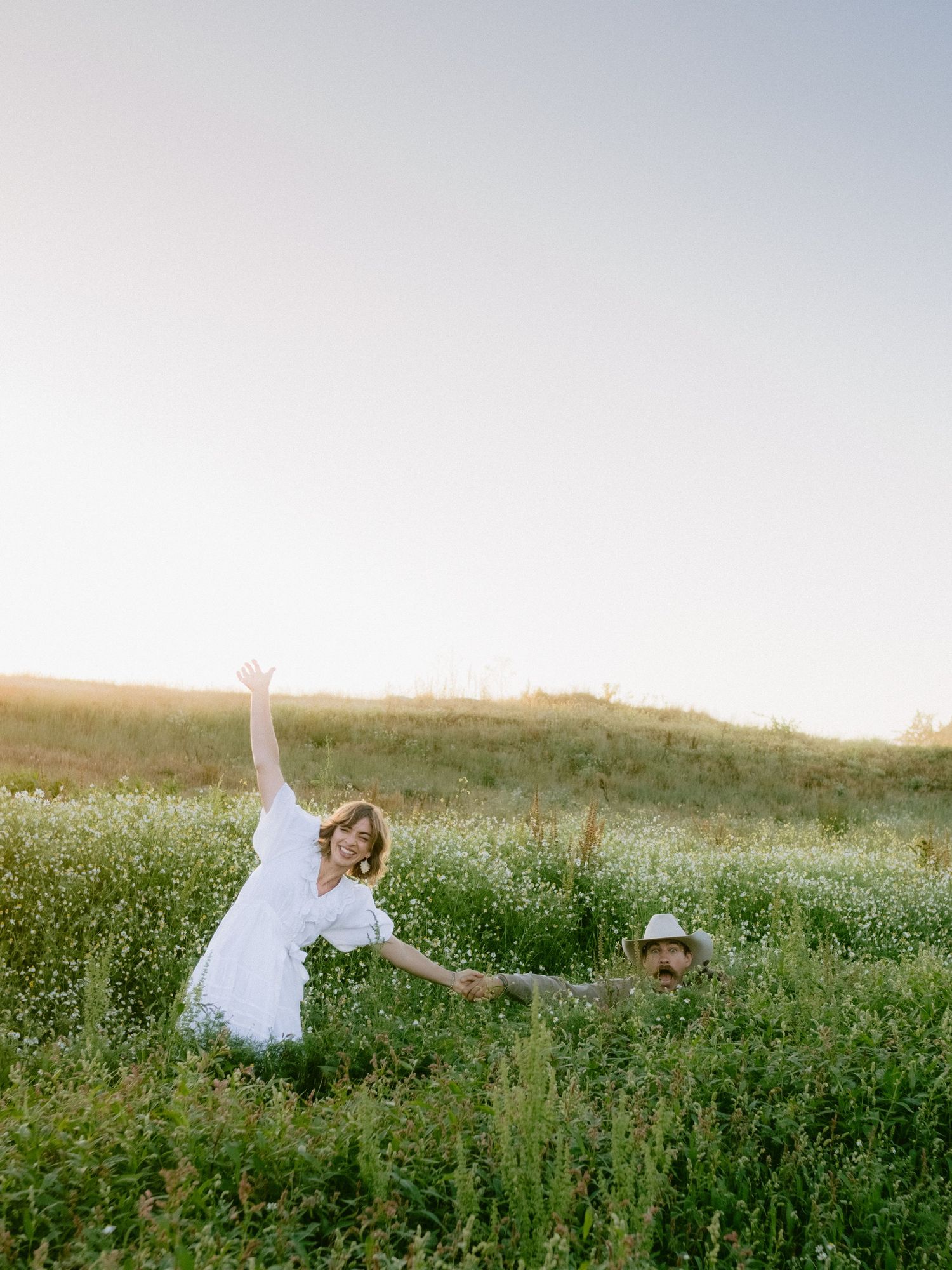 A romantic photoshoot in a field of white flowers during golden hour.