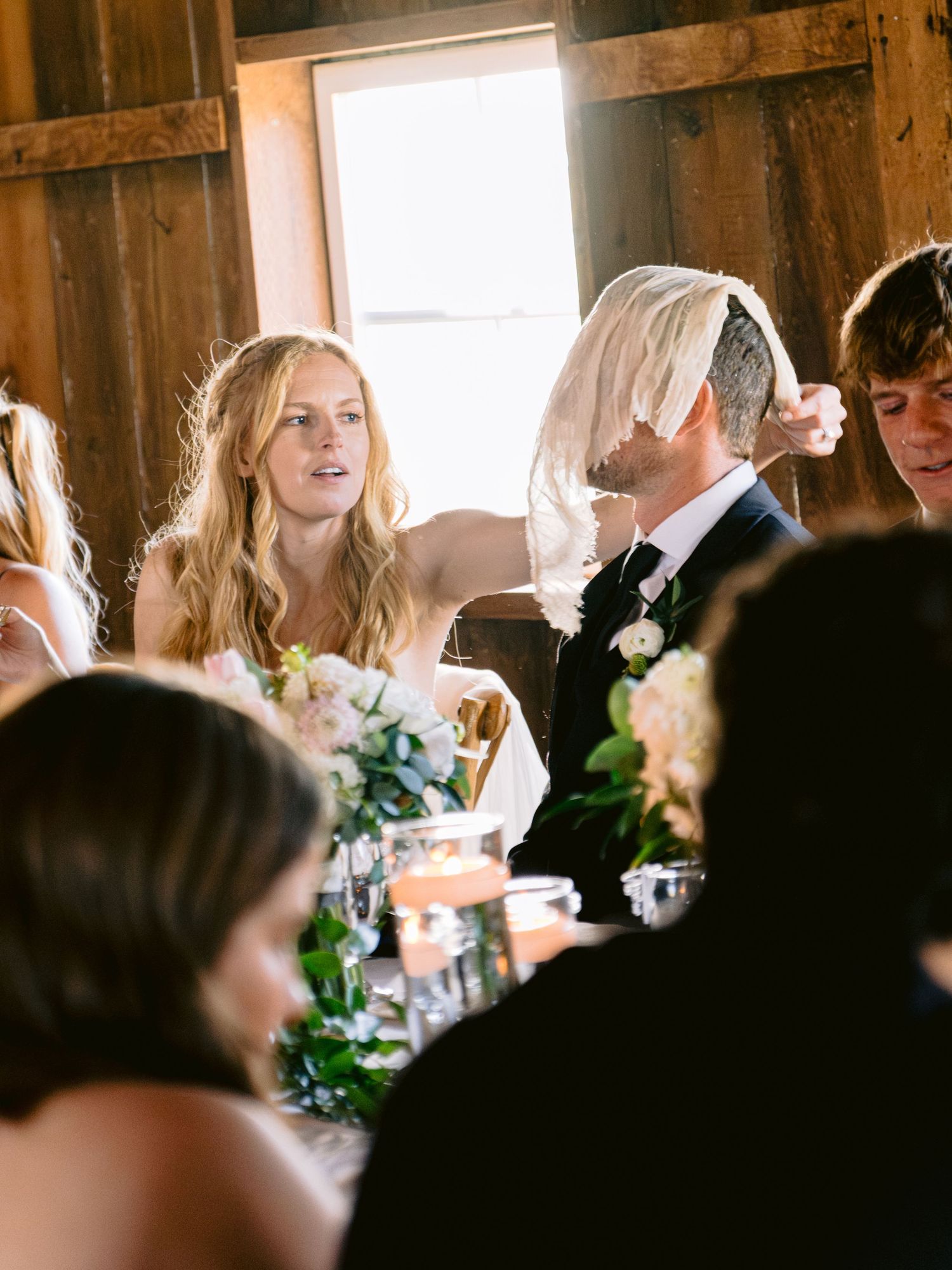 Wedding guests seated at tables inside rustic barn reception venue.