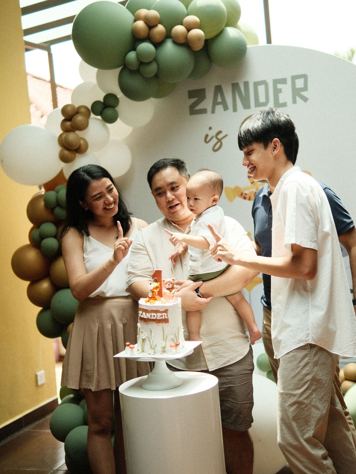 Celebration scene with green and gold balloon arch decorations at an indoor event.