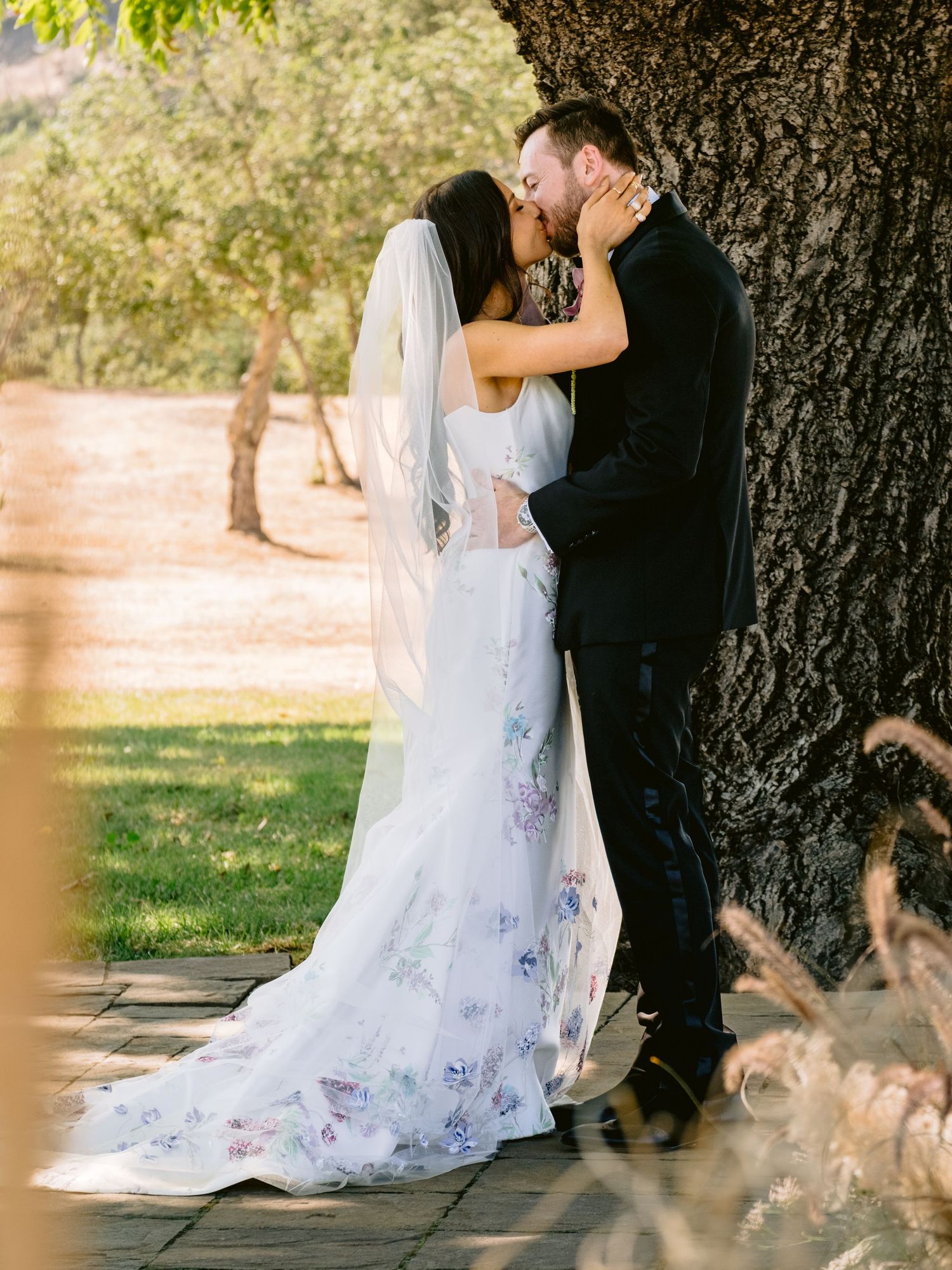 Romantic wedding portraits captured against a large tree trunk in natural lighting.