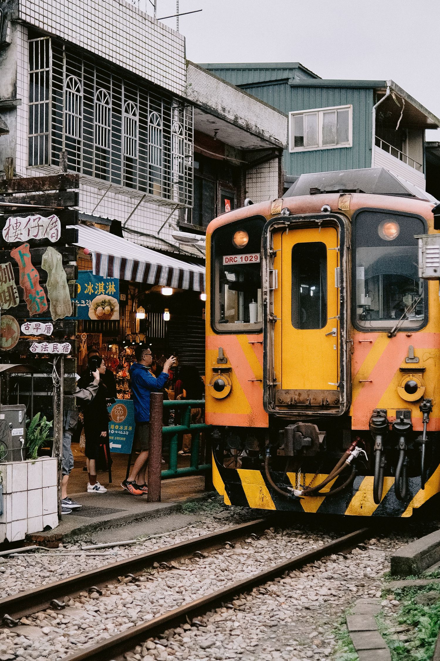 Vintage orange and yellow trains lined up at a railway station platform.
