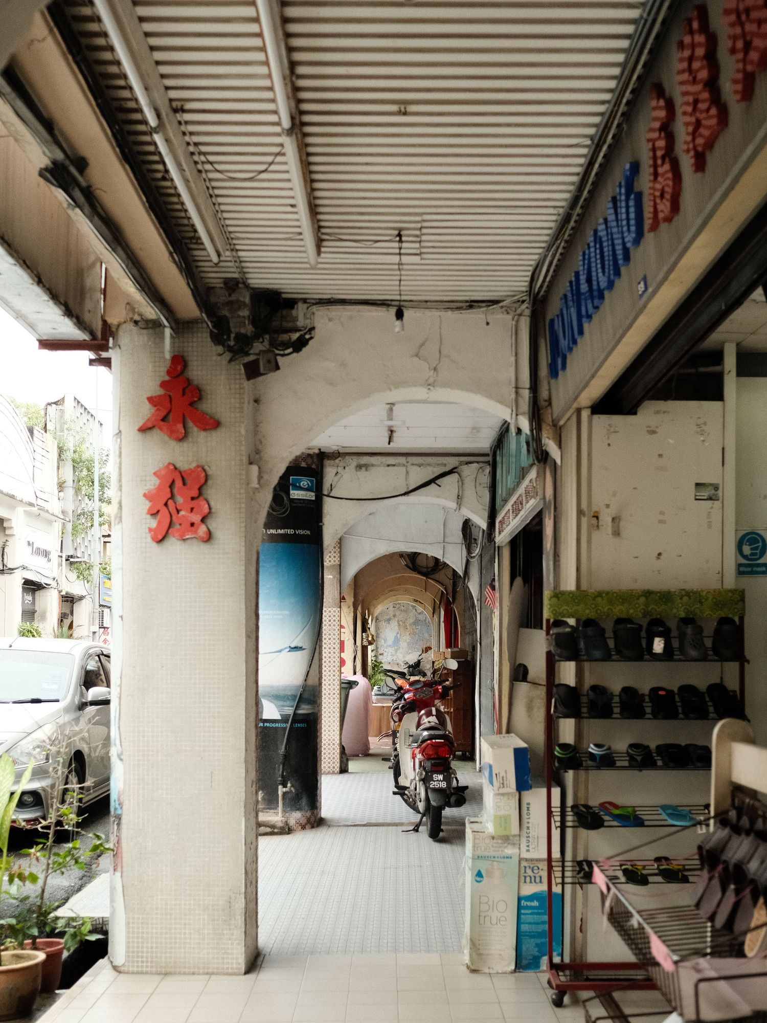 Empty covered walkway with white pillars and red Chinese characters on the wall.