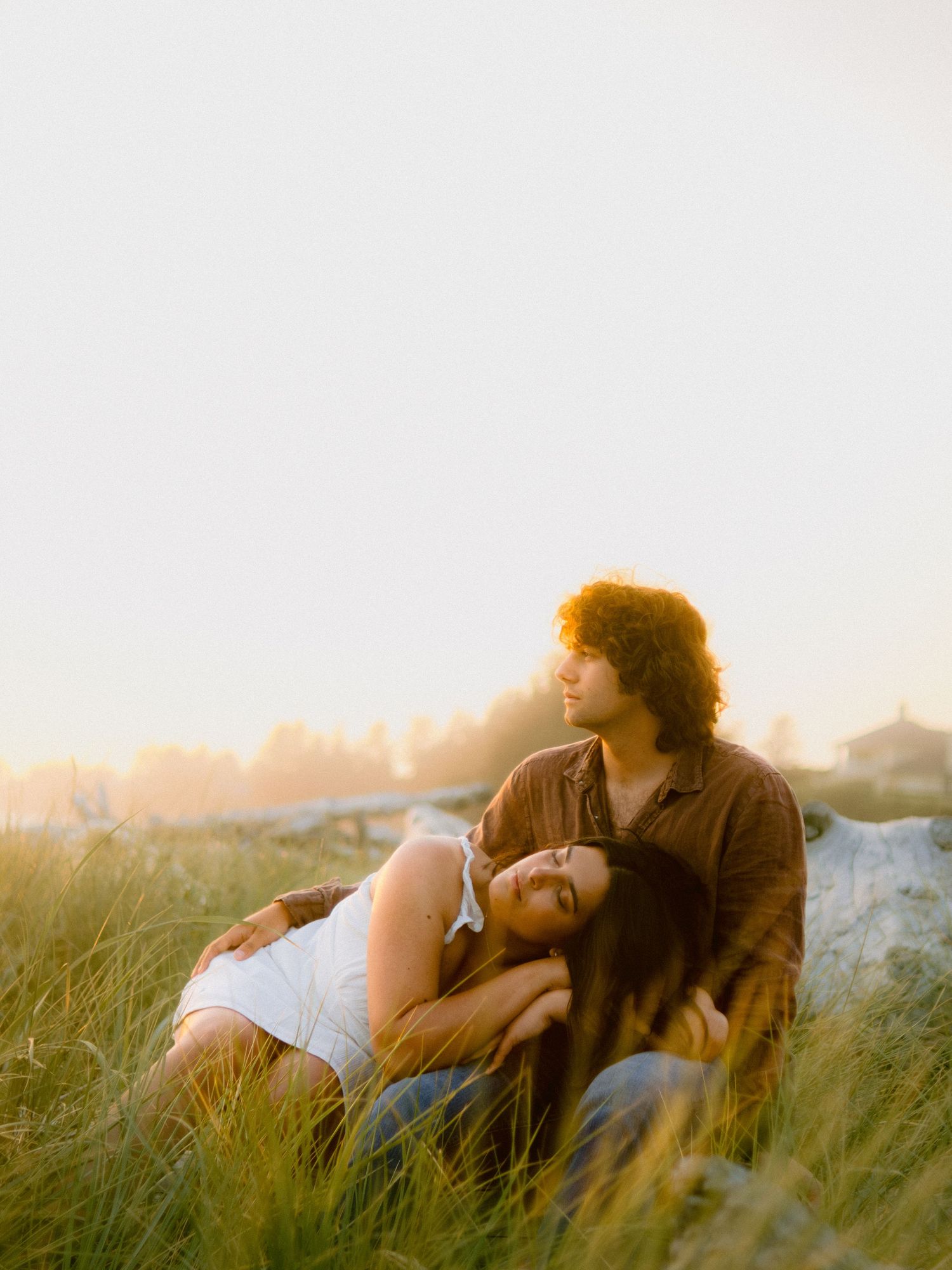 A couple relaxing together in tall grass during golden hour.
