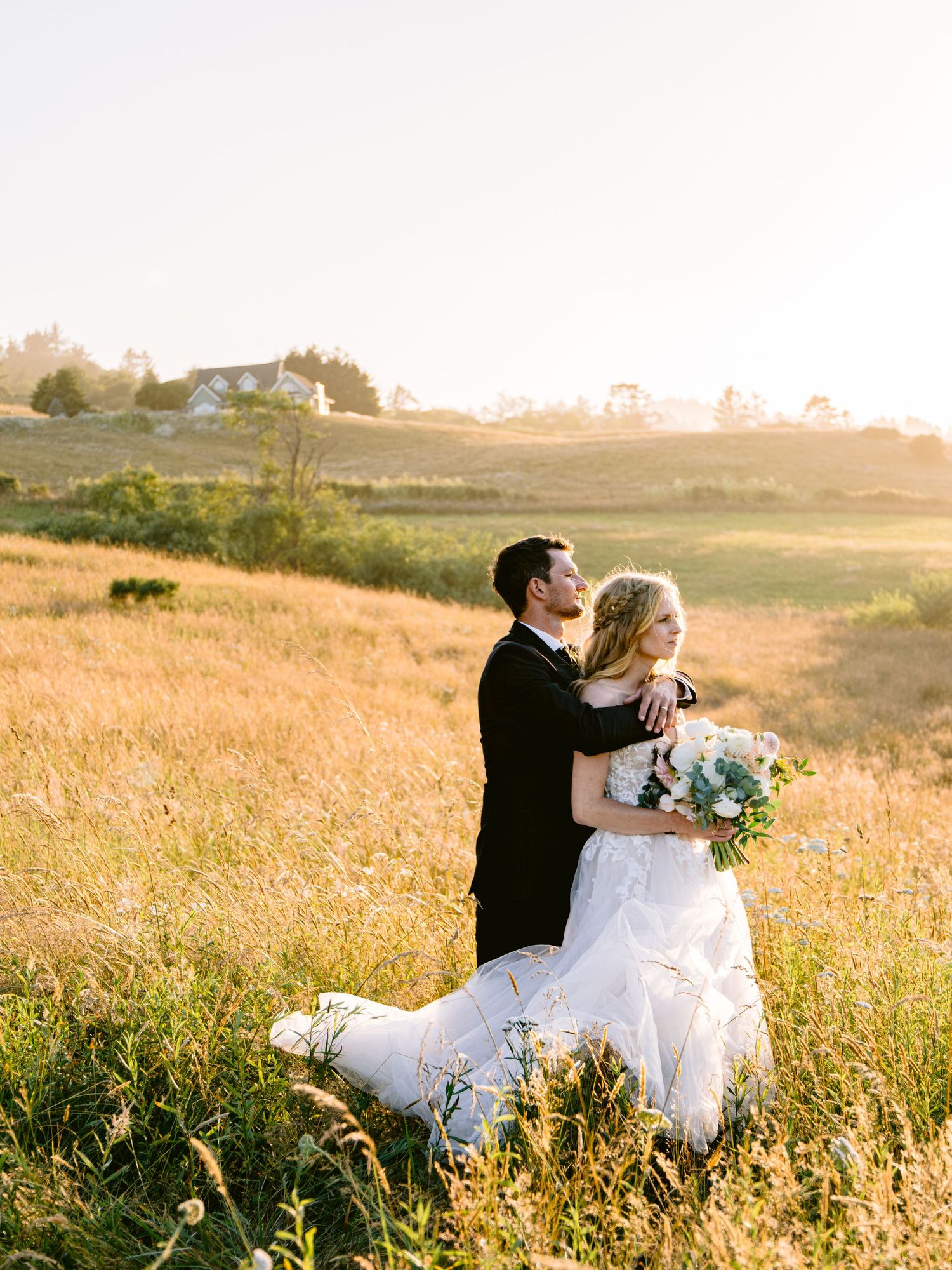 Newlyweds share an intimate moment in a sun-drenched meadow during golden hour.