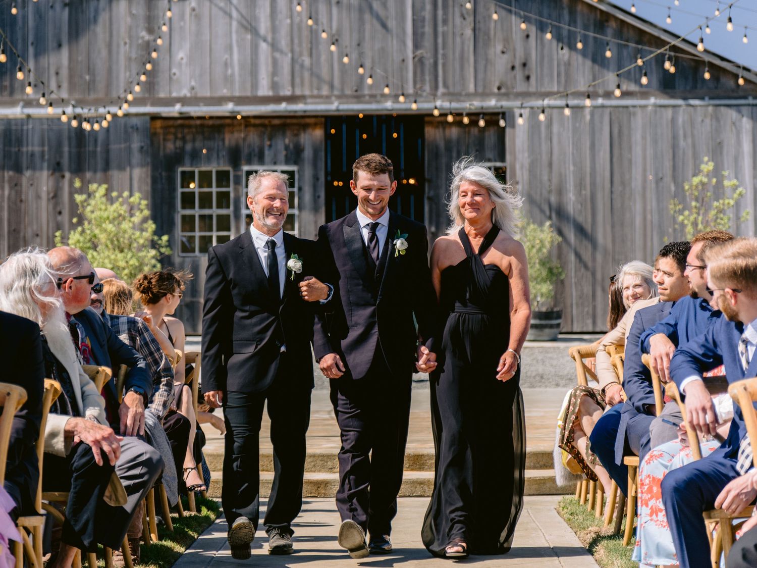 Wedding celebration in a rustic barn with string lights and guests.