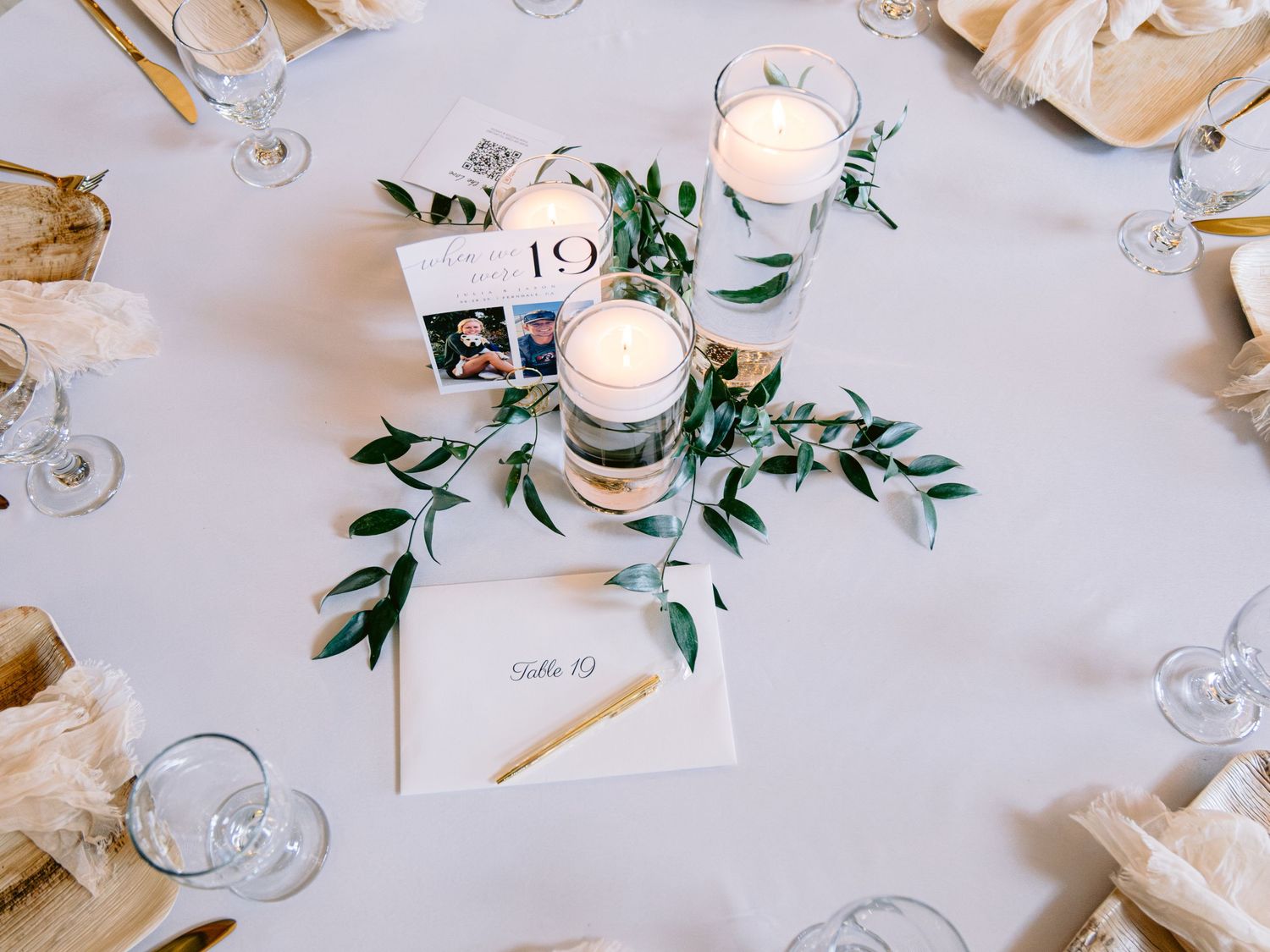 Wedding reception table setting with delicate greenery and candle decorations.