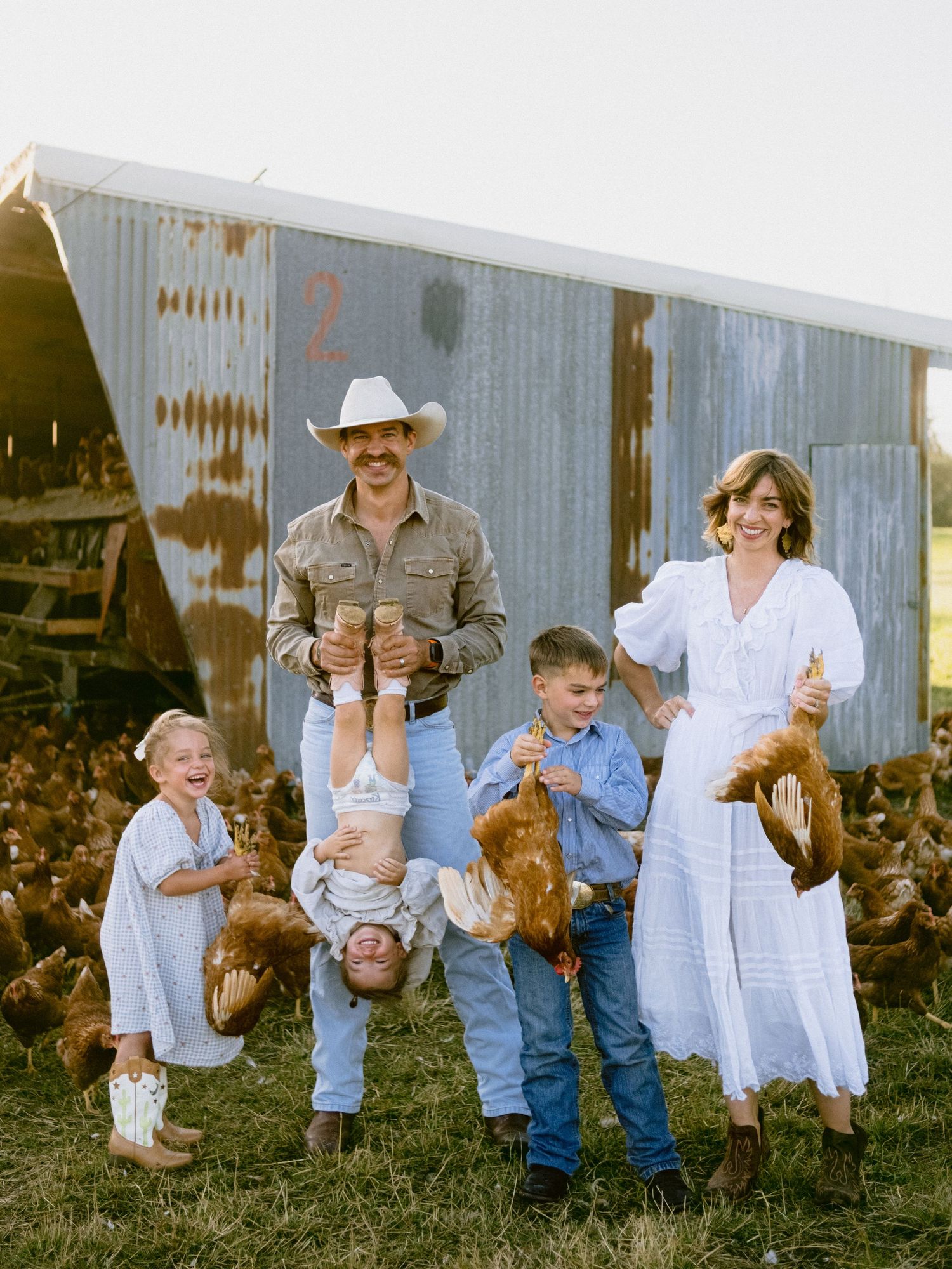 A playful family photoshoot sequence in front of a rustic barn wall showing candid moments and laughter.