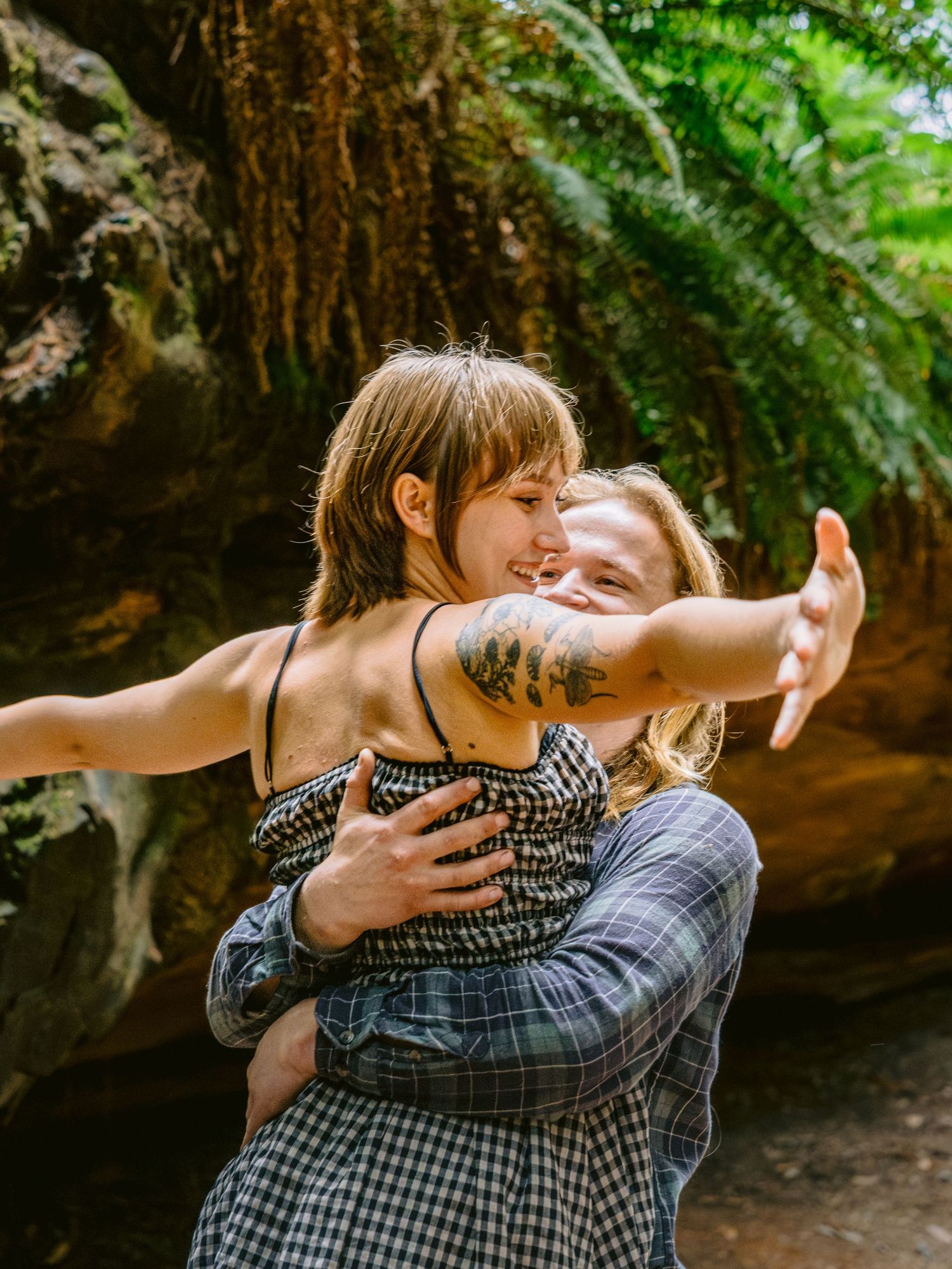 An intimate embrace captured in a lush forest setting with natural lighting.
