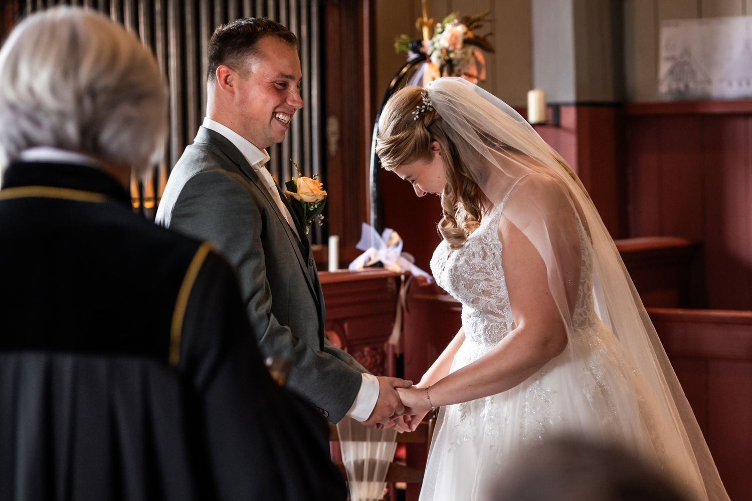 Traditional wedding ceremony takes place in a church with a bride in white dress and veil exchanging vows at the altar.