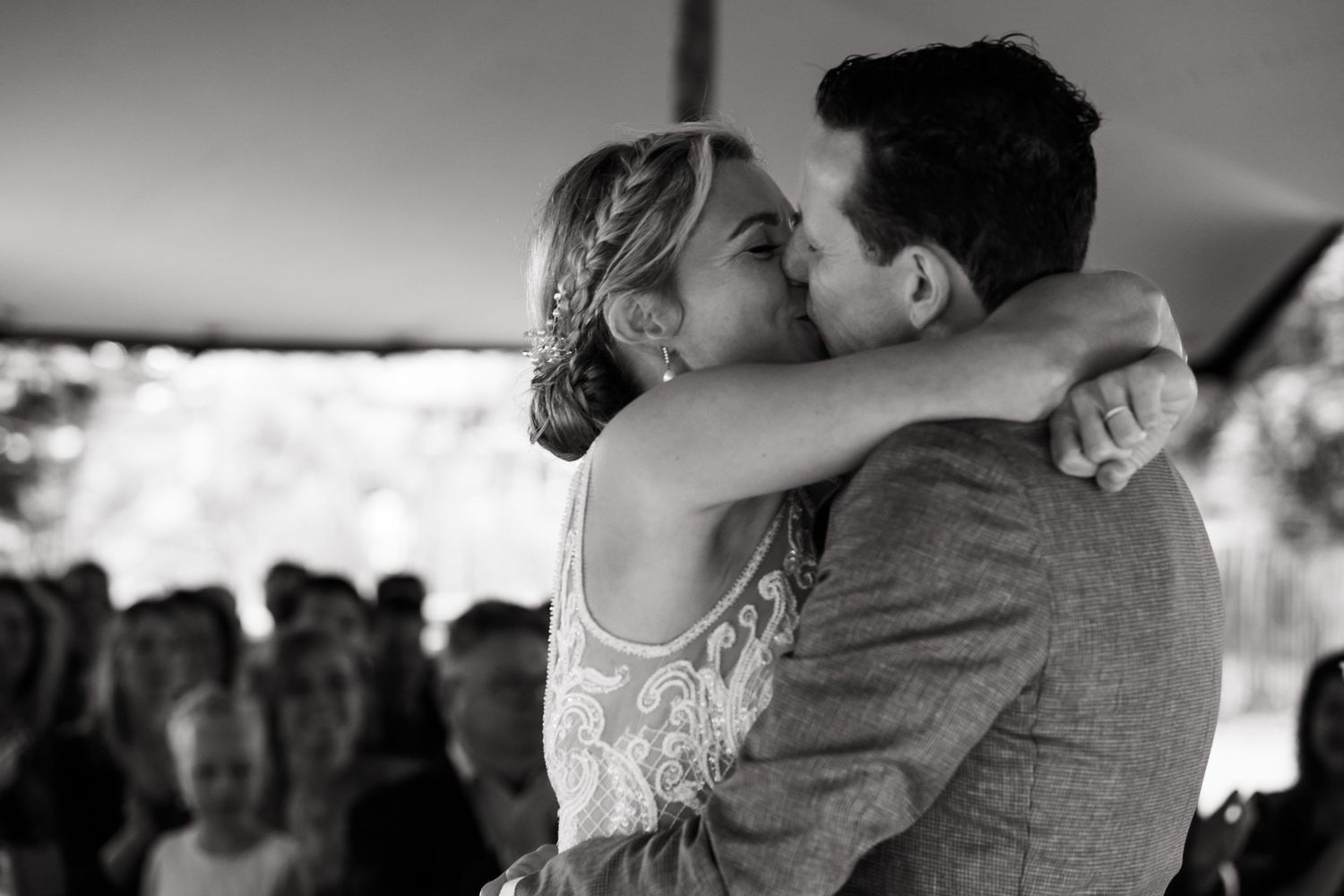 An intimate black and white photo captures a dancing couple embracing during their wedding celebration.