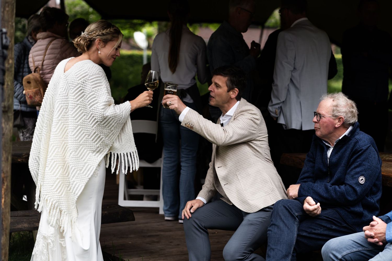Wedding celebration toast between guests under outdoor pavilion.
