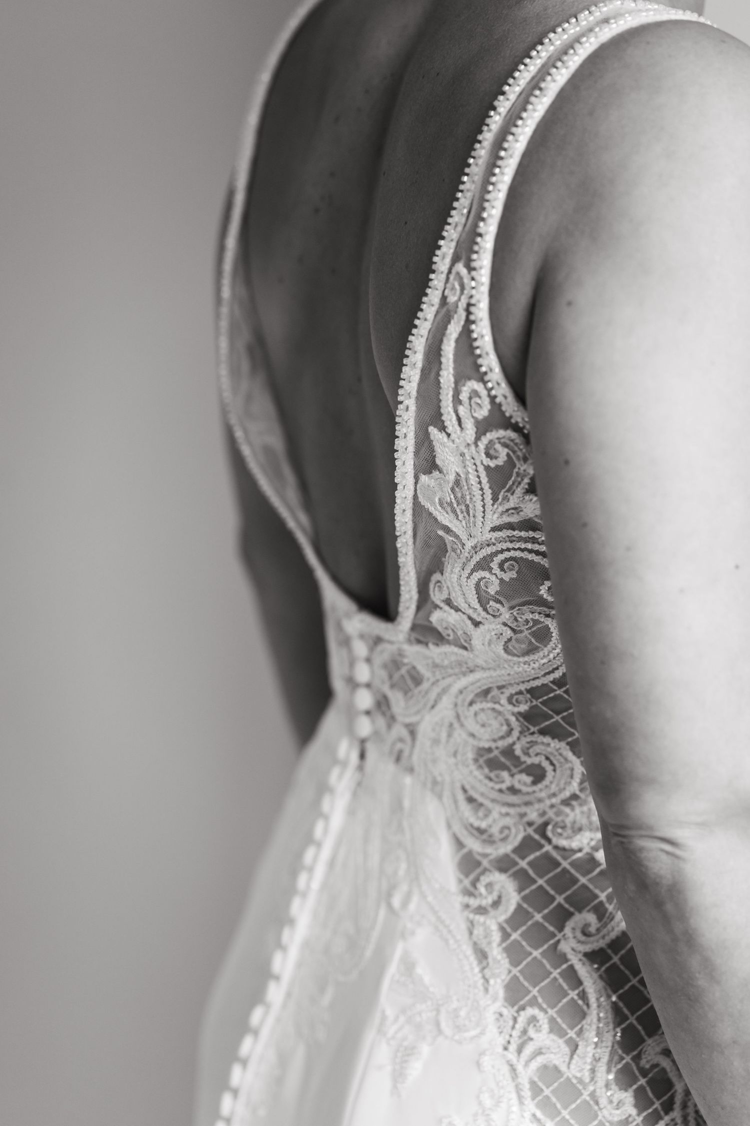 Close-up detail of delicate lace pattern on wedding dress strap.