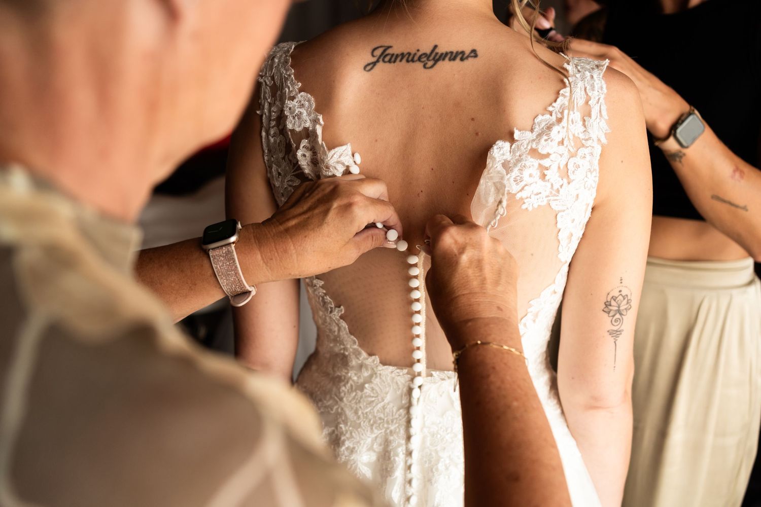 Close-up of delicate lace details and buttons on the back of a white wedding dress.