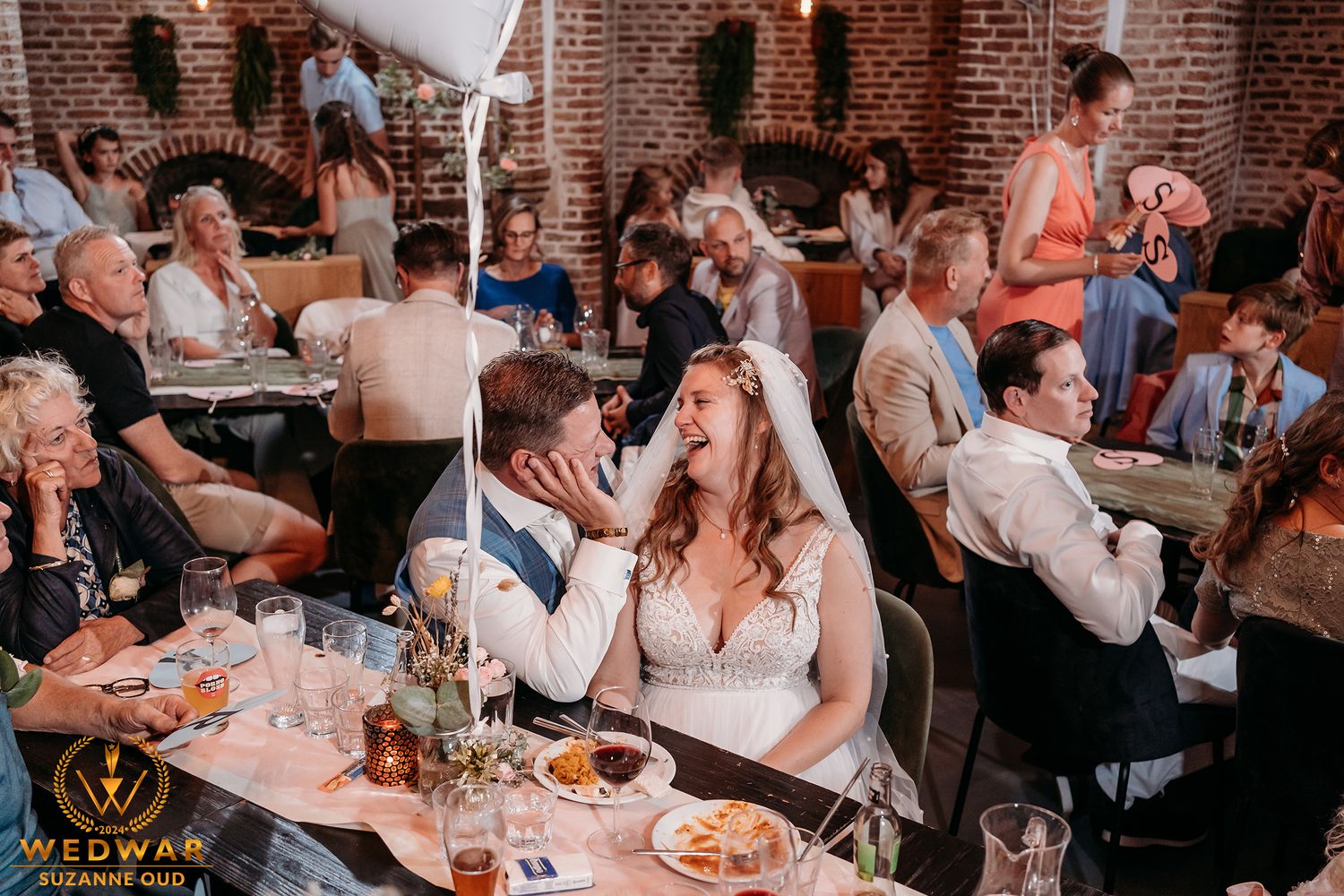 Lively wedding reception scene with guests dining and celebrating at tables.