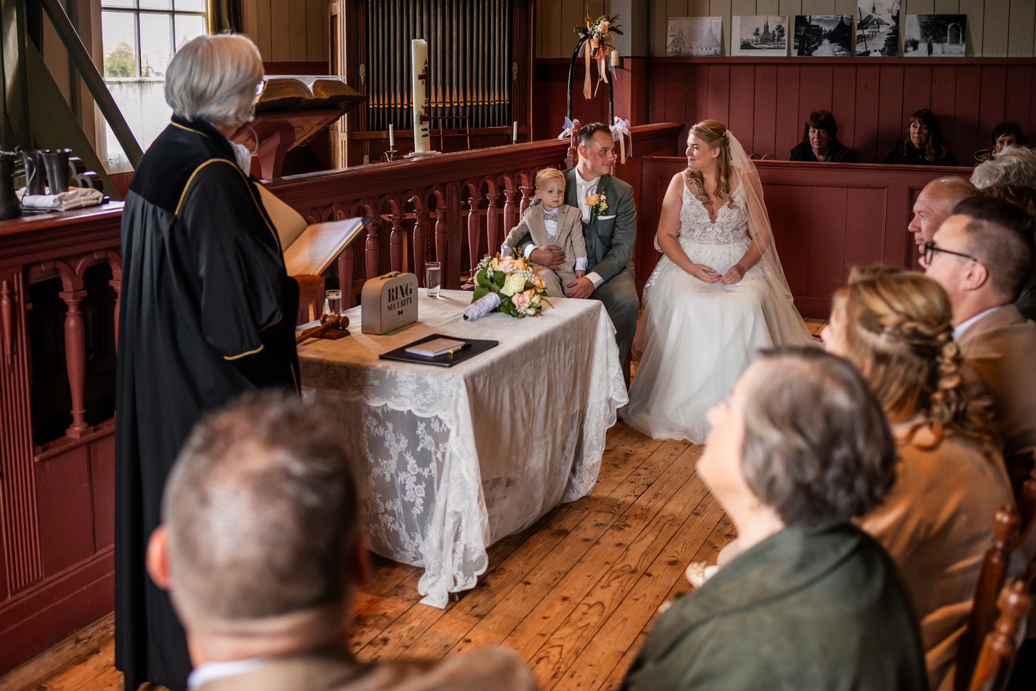 Traditional wedding ceremony in wooden church interior with officiant at altar.