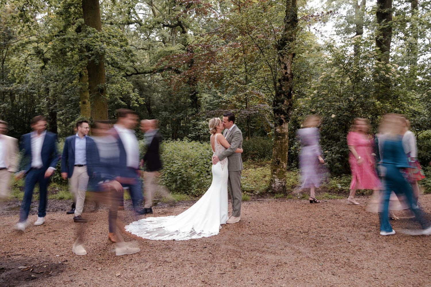 Creative wedding photo with couple in center while guests create motion blur effect walking past.