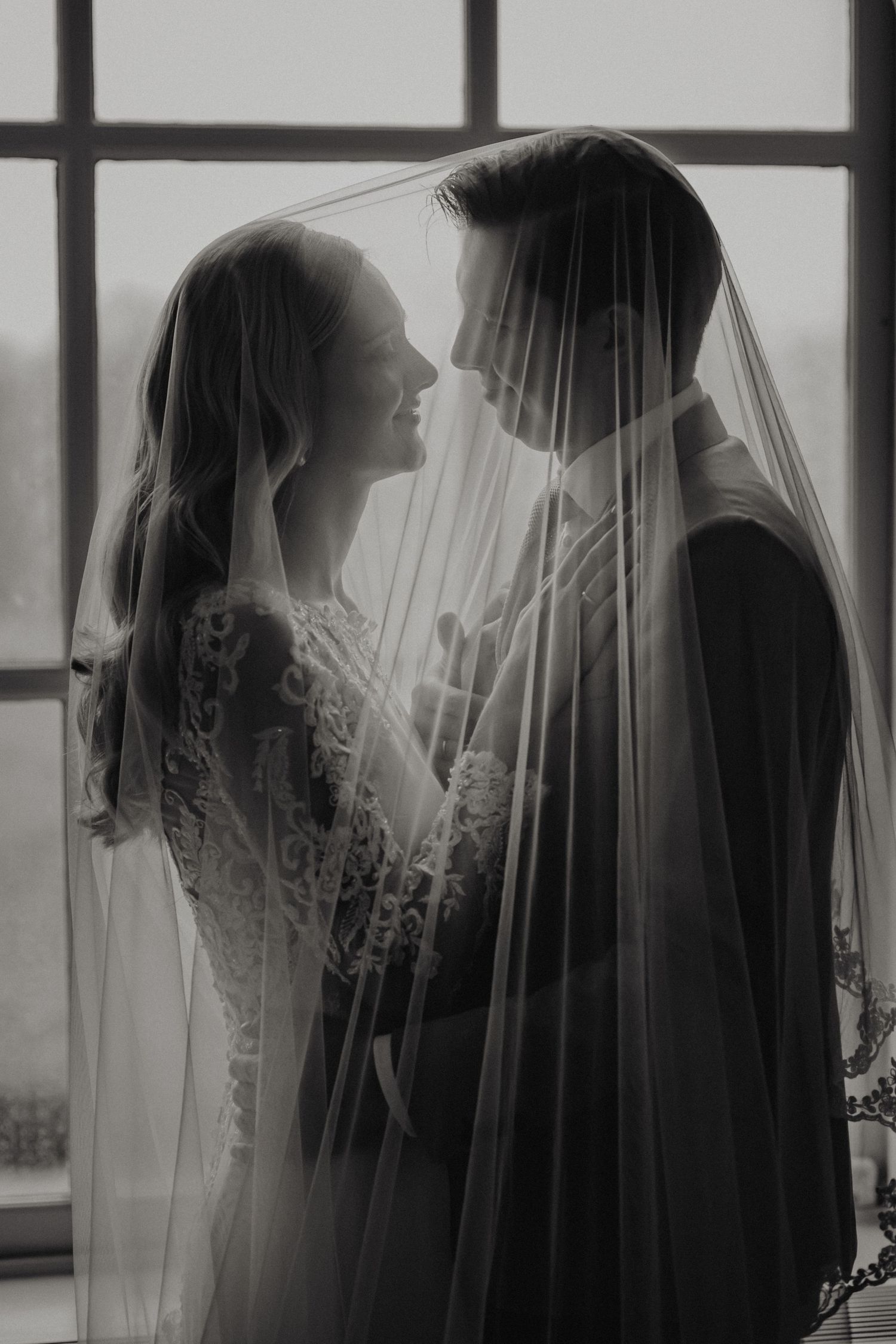 A black and white photo series showing silhouettes of a bride and groom in romantic poses behind a sheer veil.
