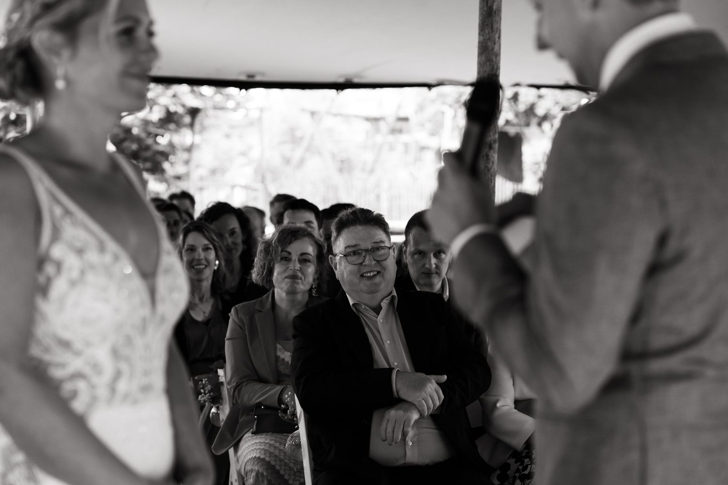 Black and white photo of wedding ceremony guests watching under a tent canopy.