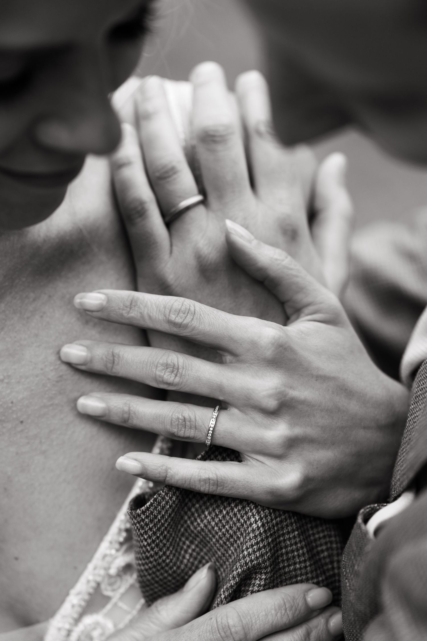 A black and white close-up of hands with wedding rings in an intimate embrace.