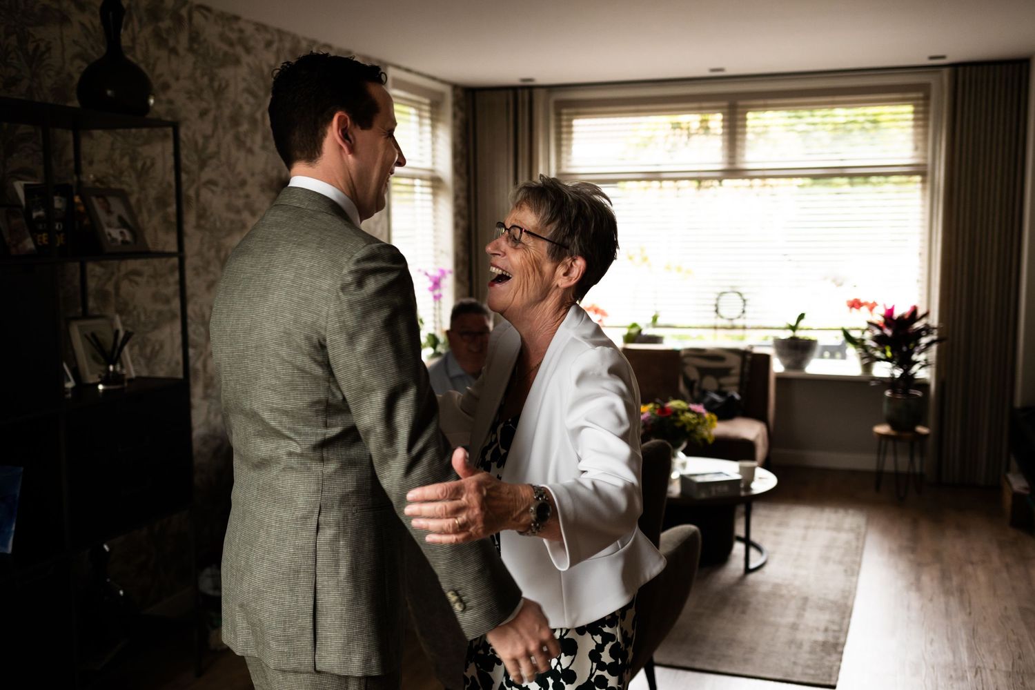 Two people share an intimate dance moment in a rustic home setting with natural light streaming through windows.