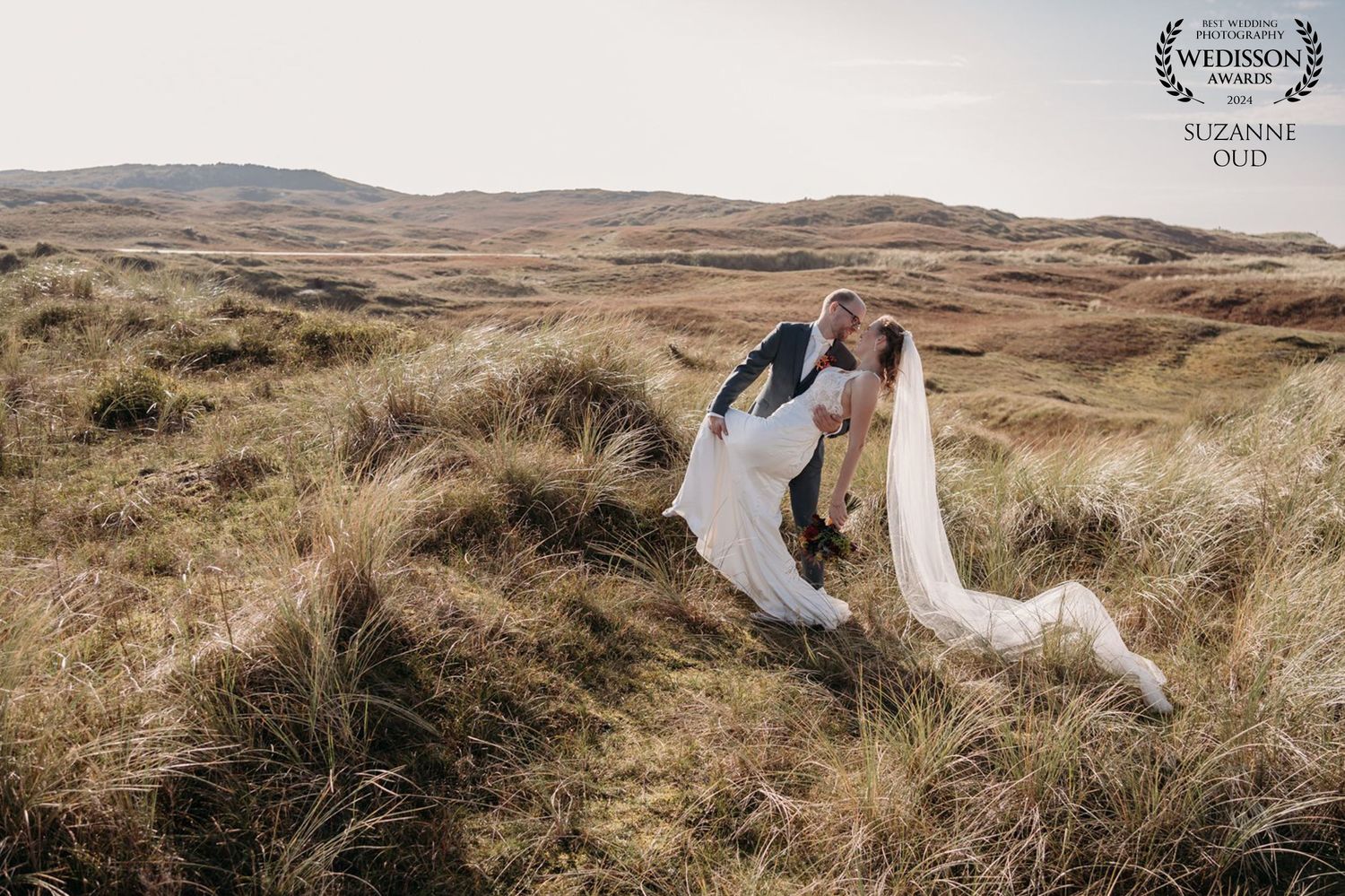 Wedding couple with flowing dress photographed in dramatic windswept highland landscape.