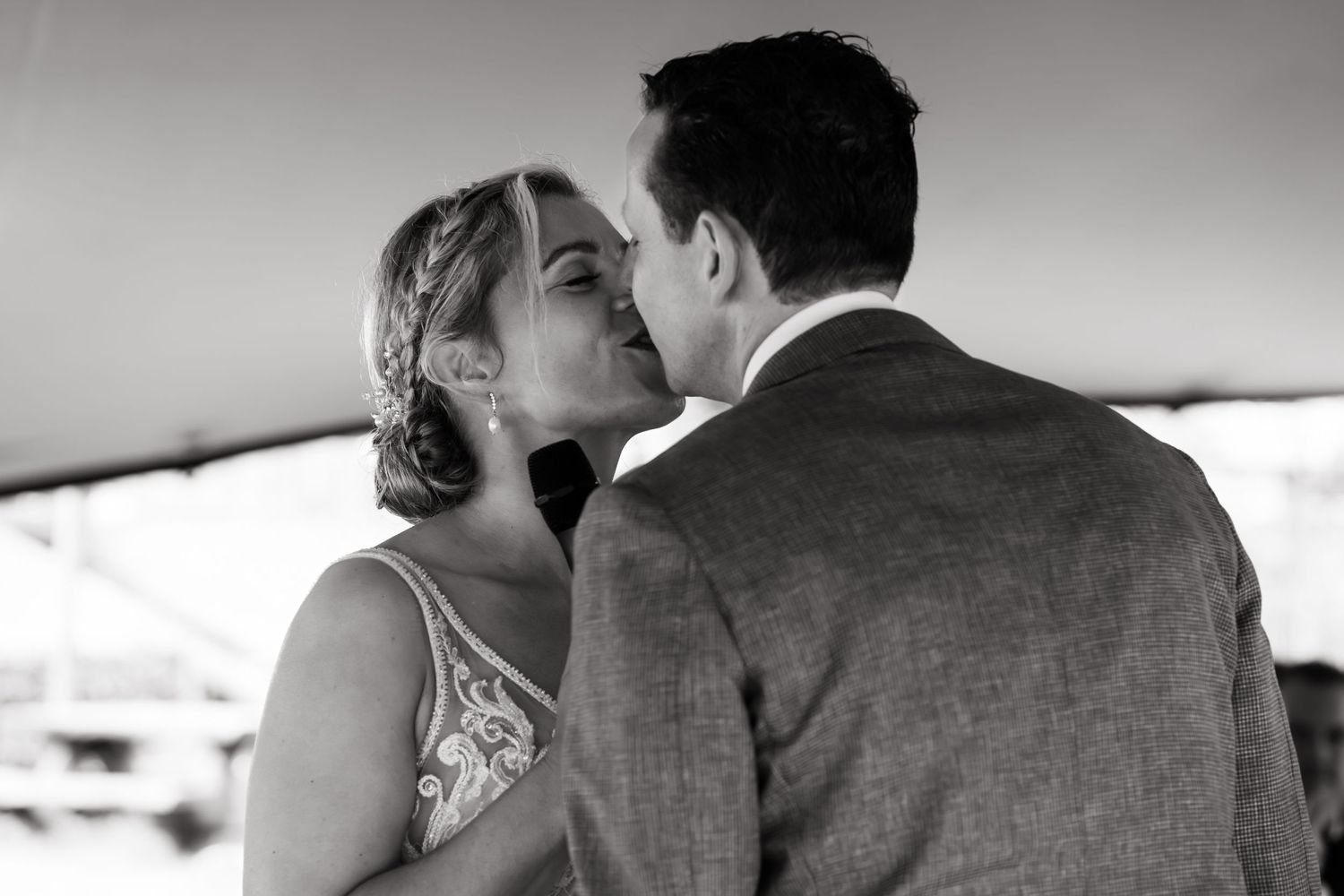 A romantic black and white portrait of newlyweds sharing an intimate moment under a tent.