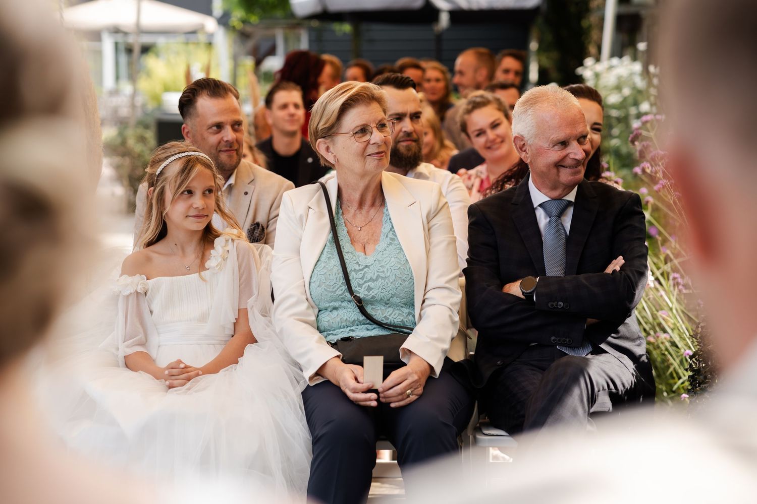 Wedding guests watch attentively during an outdoor ceremony with expressions of joy and emotion.
