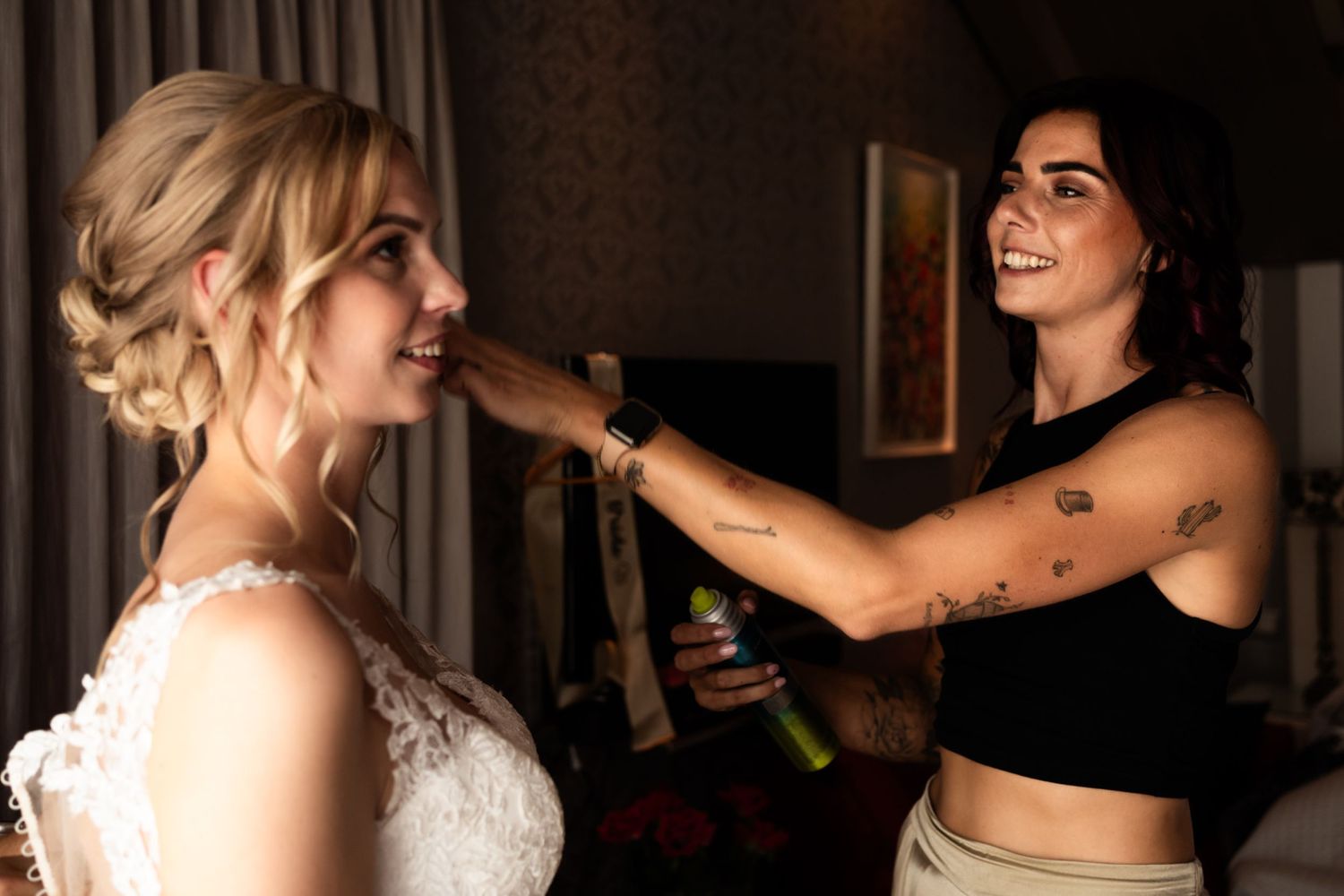Final touches being applied to bride's hair during wedding preparations in a warmly lit room.