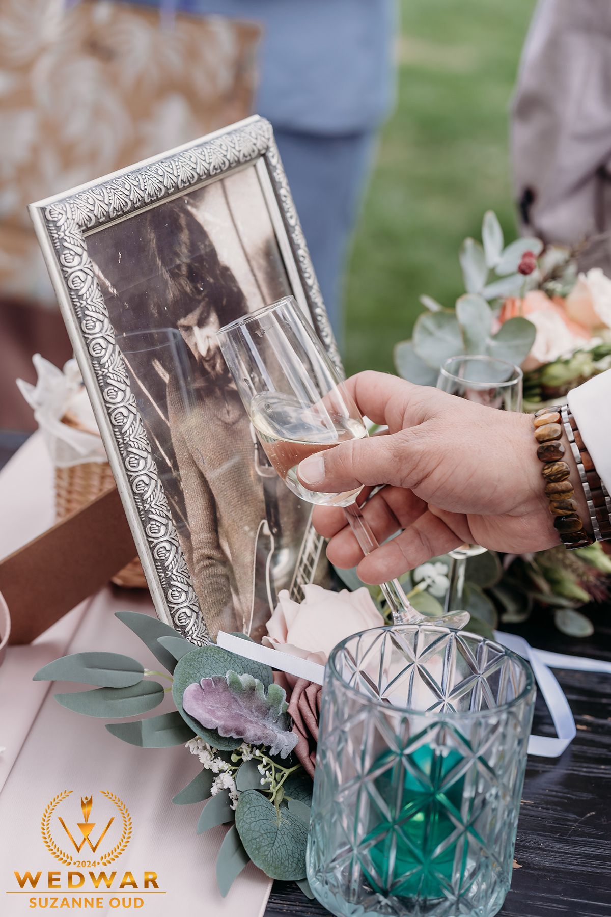 Ornate silver frame and champagne glass on decorated wedding table.