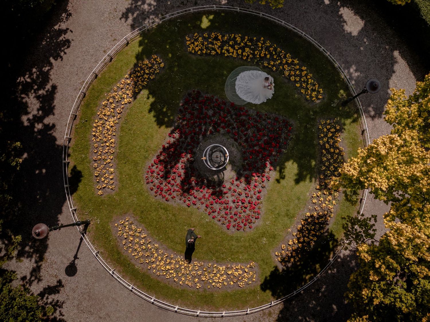 Aerial view of thousands of lit candles arranged in a spiral pattern on grass at dusk creating a glowing mandala design.