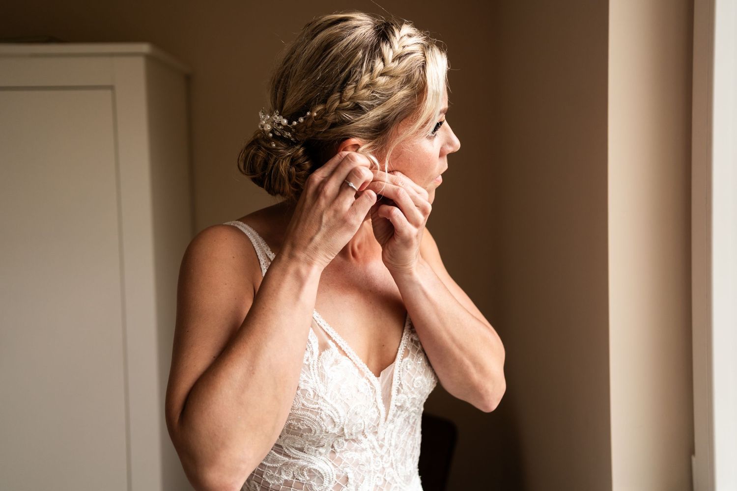 Close up shot showing intricate bridal hairstyle and white lace dress details.