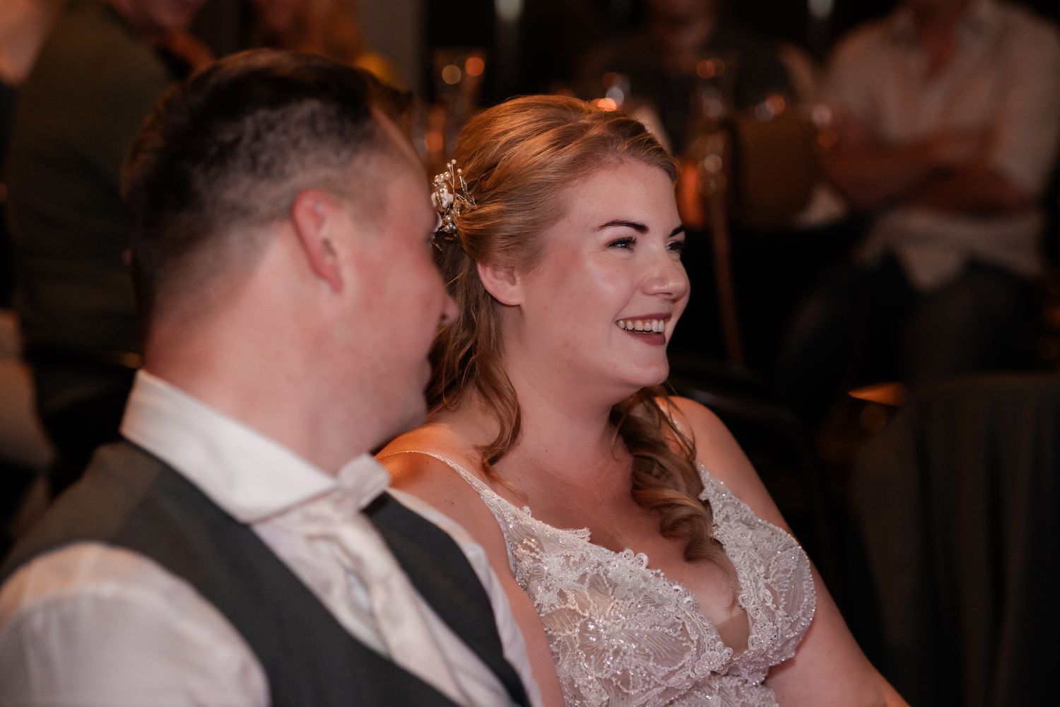 A bride and groom share a candid laughing moment together during their wedding reception.