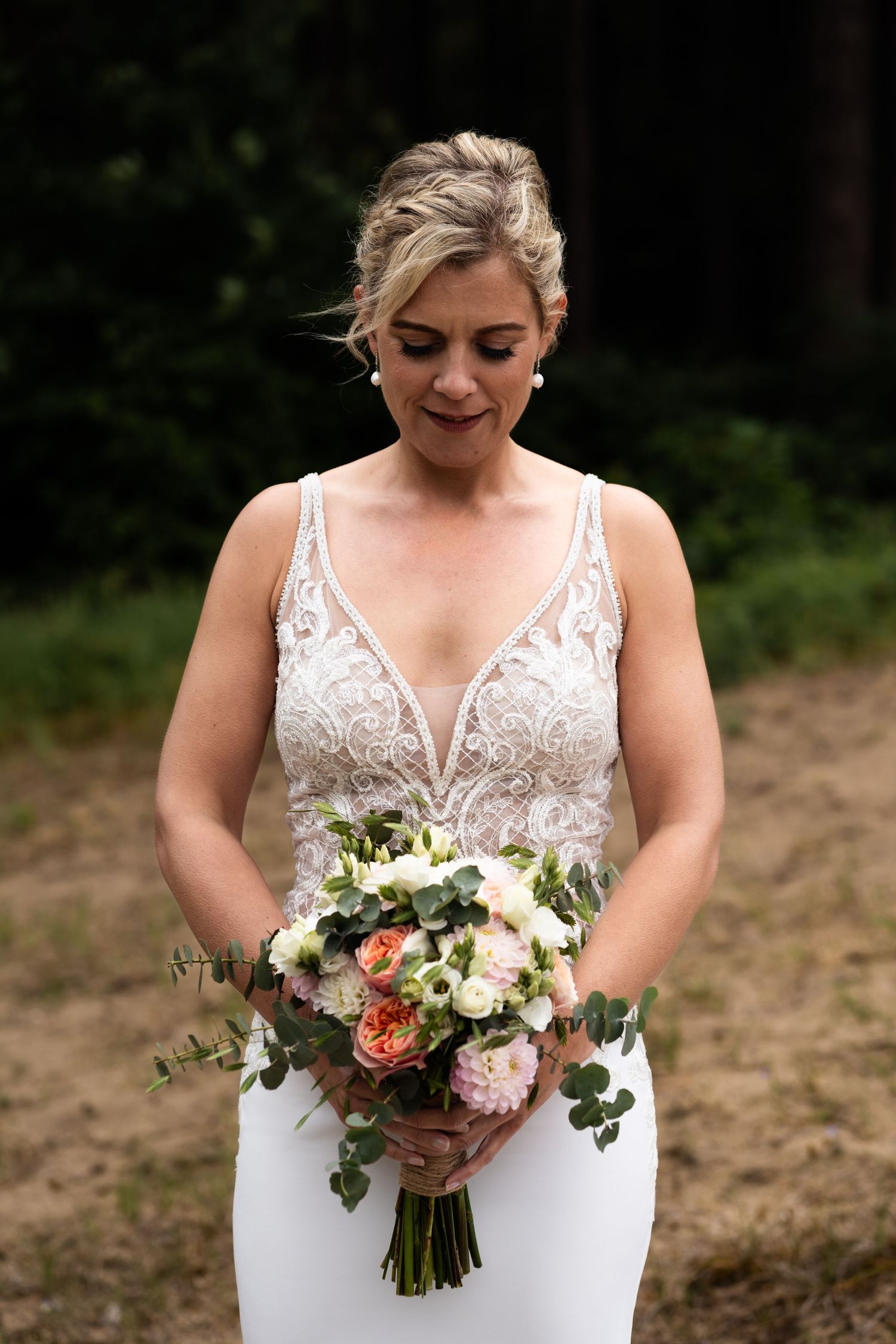 Classic bridal portrait with white floral bouquet against forest backdrop.