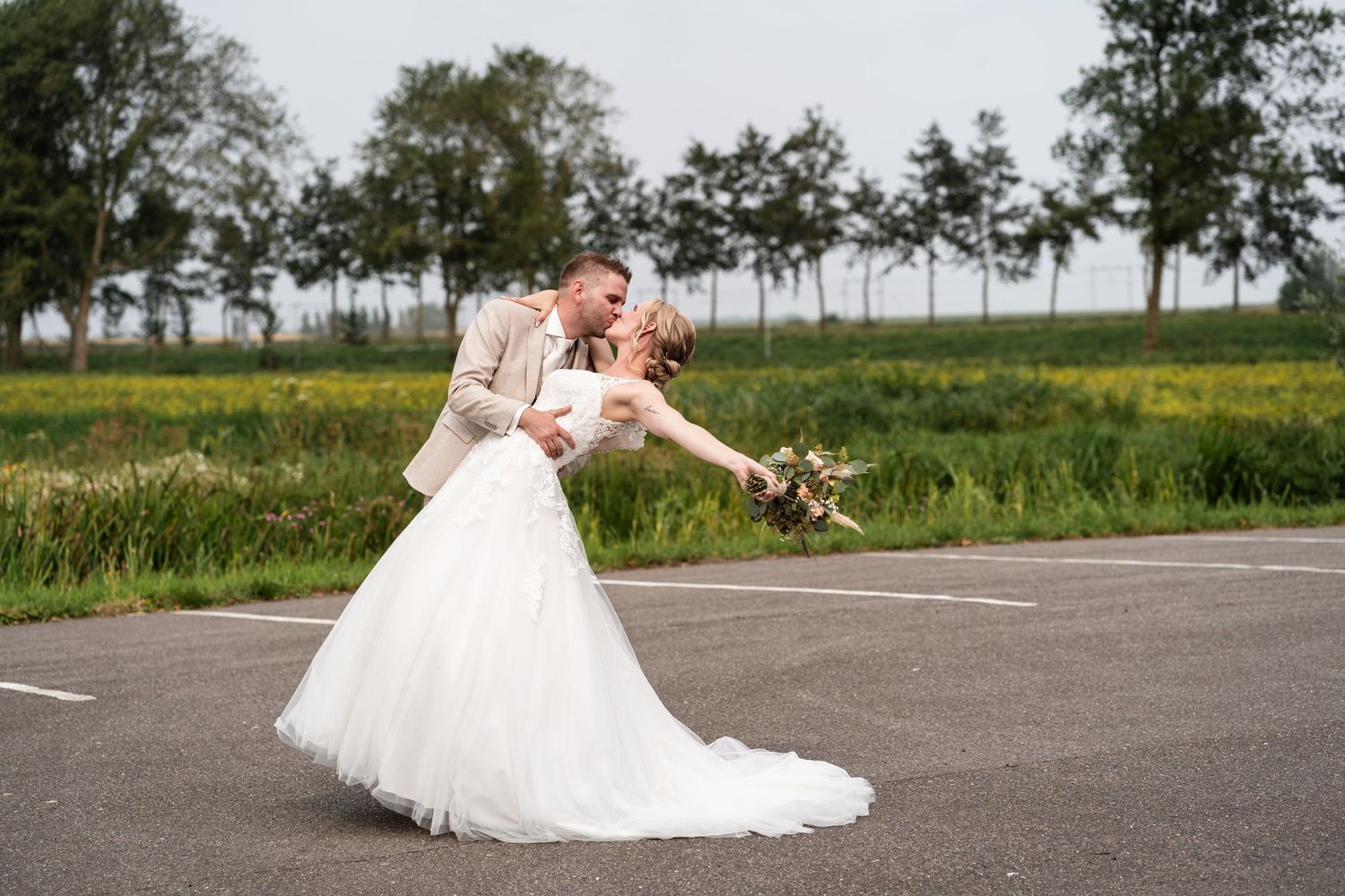 Newlyweds dancing together on an empty road with countryside in the background.
