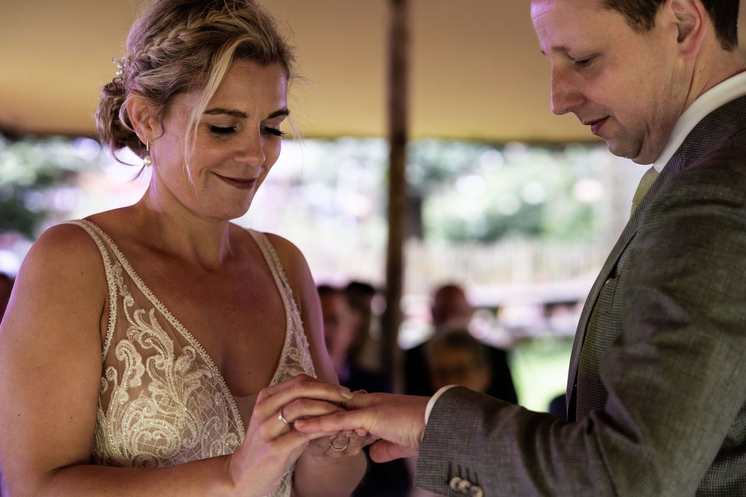 A tender moment during a ring exchange ceremony under a covered outdoor venue.
