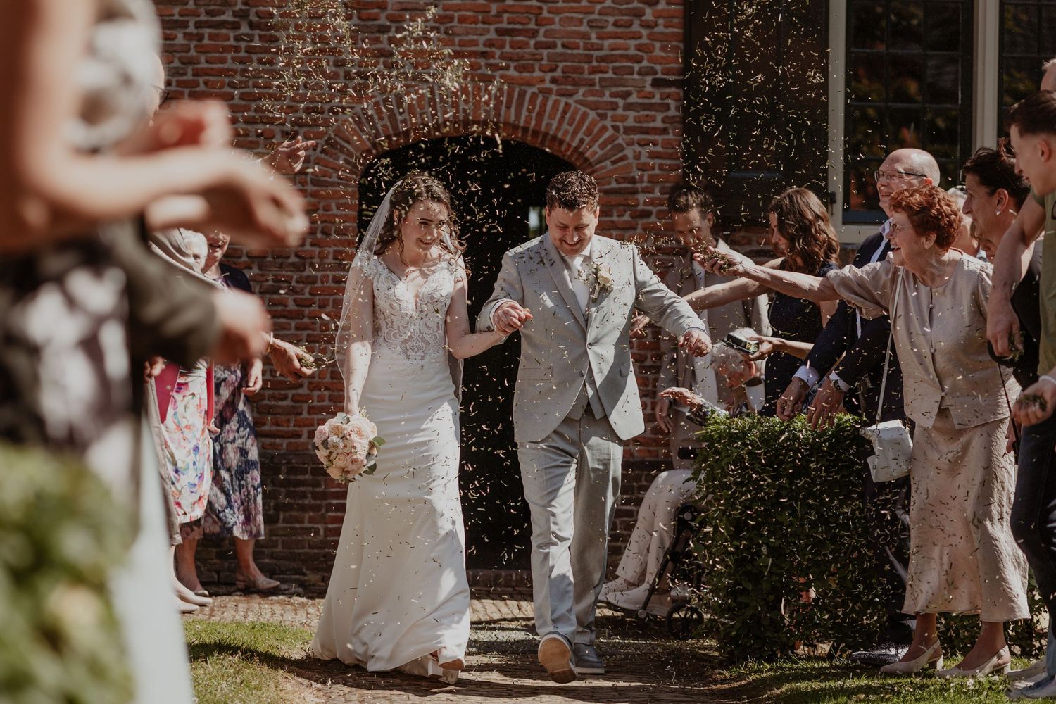 Bride and groom exit church as guests toss confetti during joyful outdoor wedding ceremony celebration.