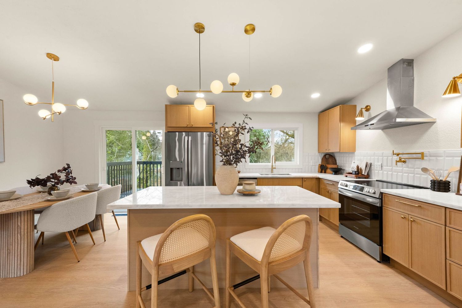 Modern open concept living space with pendant lights, white kitchen cabinets, and natural wood accents throughout.
