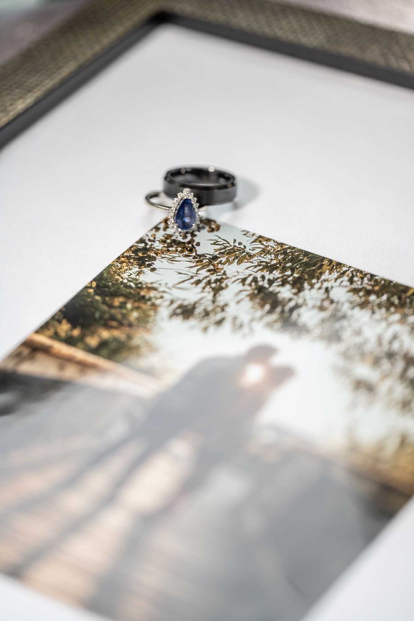 Wedding ring with blue gemstone placed on corner of framed photograph.