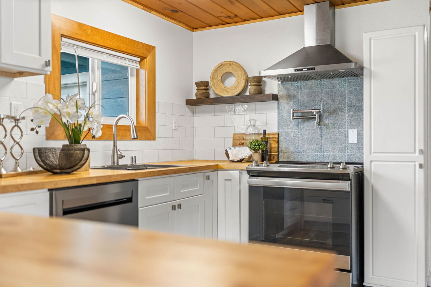Contemporary kitchen featuring white cabinets, butcher block countertops, and stainless steel appliances.