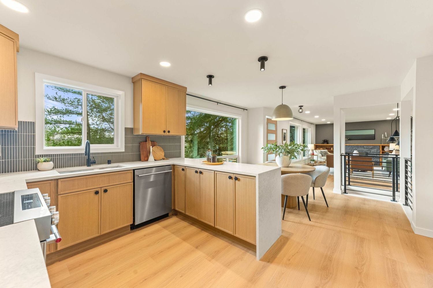 Modern kitchen with light wood cabinets, stainless appliances, and open concept design featuring natural light.