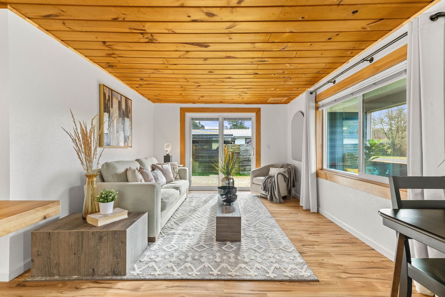 Modern kitchen with wood plank ceiling features sleek white cabinets, stainless appliances and pendant lighting over island.