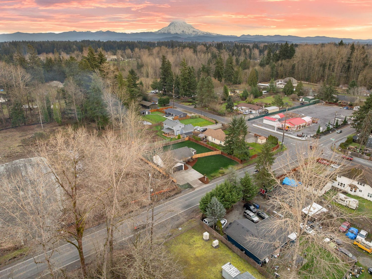 Aerial panoramic view of a suburban neighborhood with Mount Rainier visible in the background during sunset.