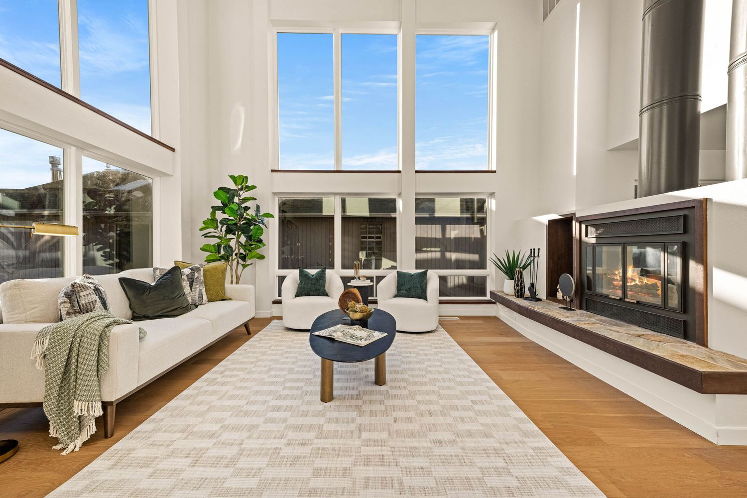 Bright living space with floor-to-ceiling windows, wood floors, and mountain views.