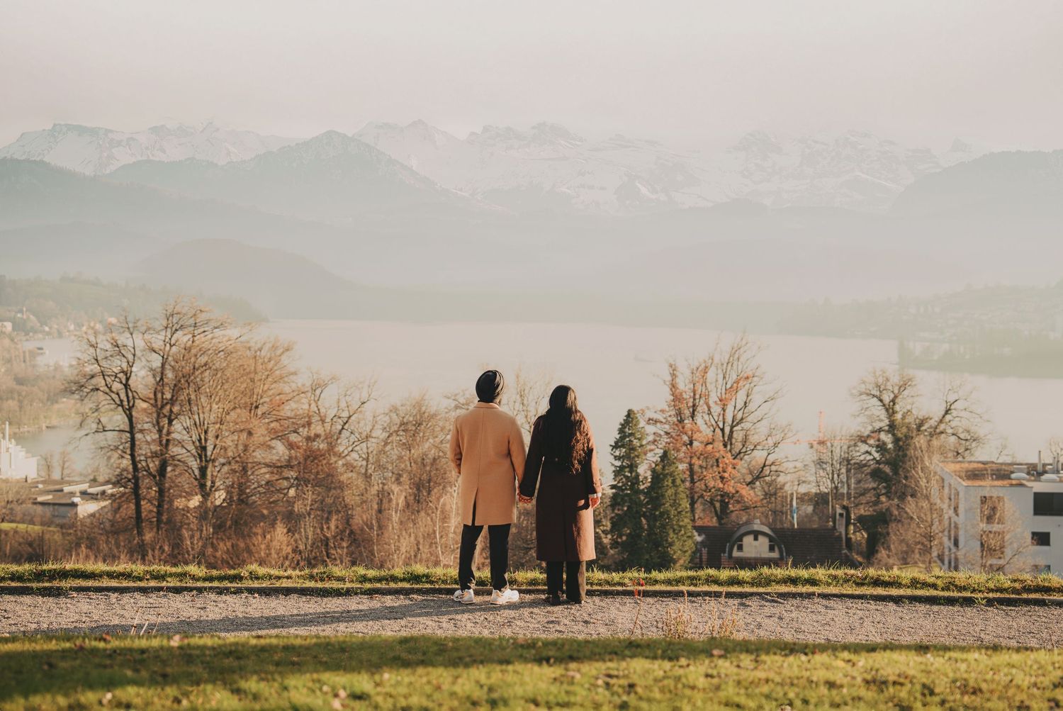 Couple standing hand in hand overlooking a scenic misty mountain and lake landscape in autumn.