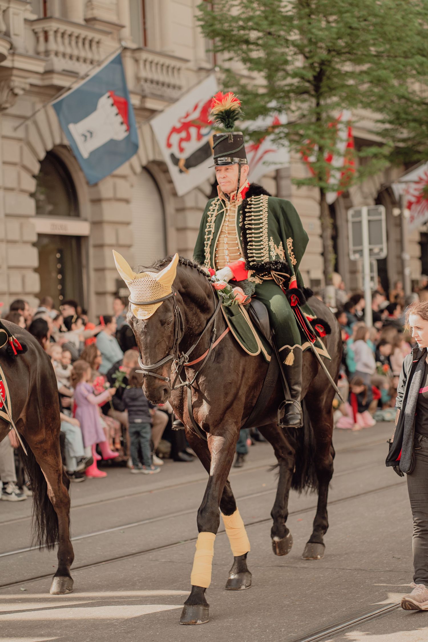 Rider in green historical military uniform on horseback during a traditional city street parade.