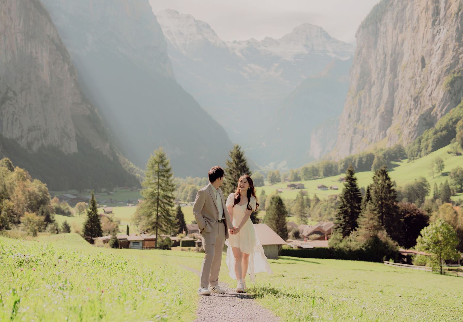Couple sharing a tender moment on a grassy path in a stunning Swiss mountain valley.